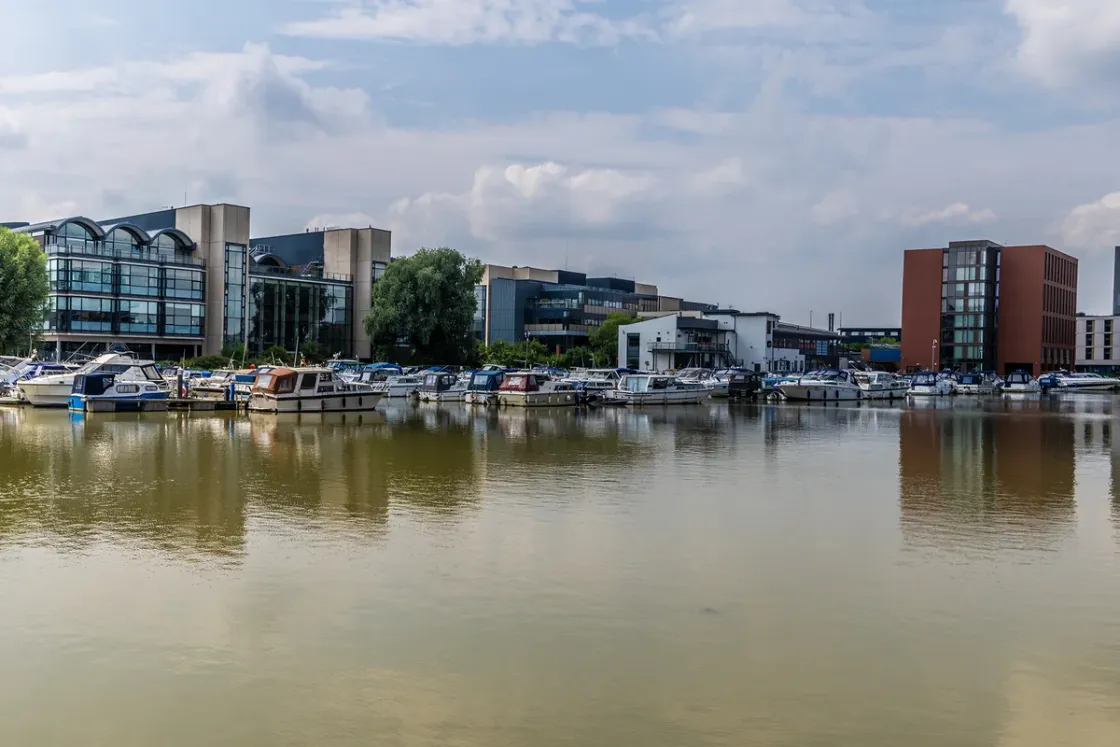 Boats moored on Brayford Pool in Lincoln with the university buildings along the far side