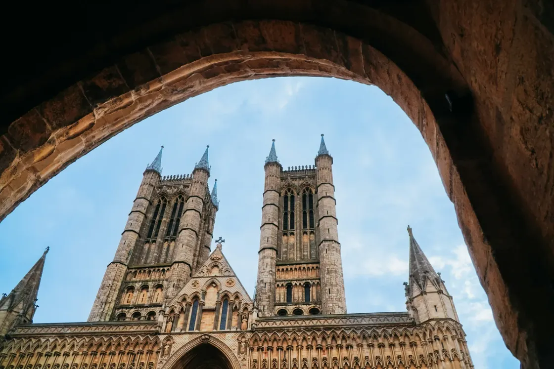 The west front of Lincoln Cathedral framed by a stone archway