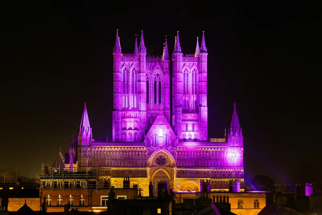 Lincoln Cathedral floodlit in purple against a black night sky
