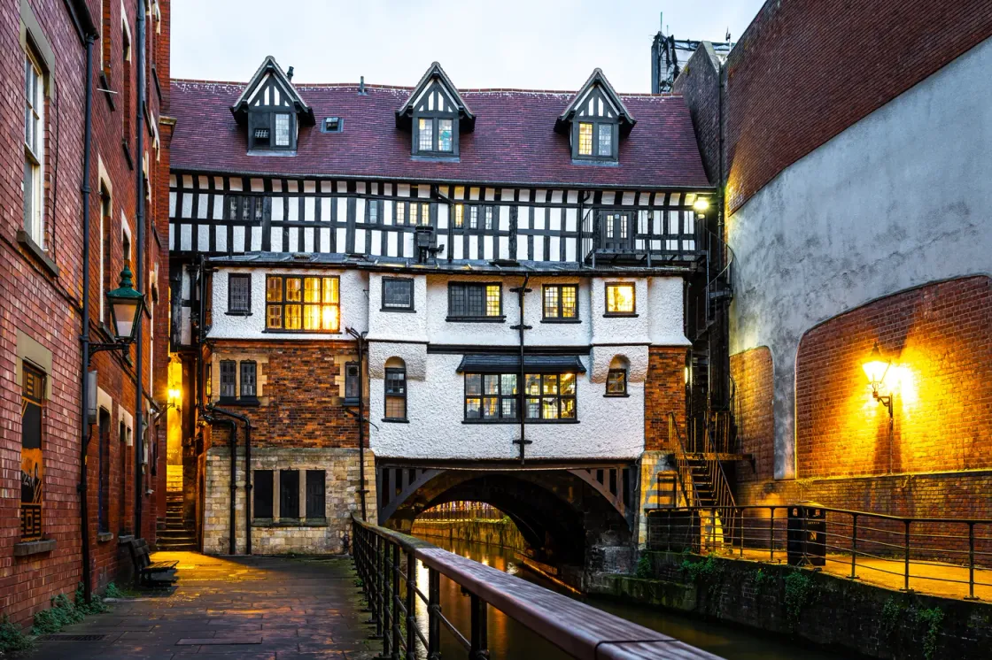 The Glory Hole in Lincoln at dusk, the timber-framed building spanning the River Witham with lit windows