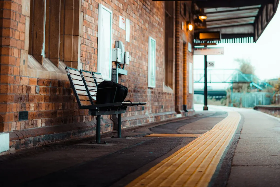 An empty platform at Lincoln railway station, bench and departure board under the canopy