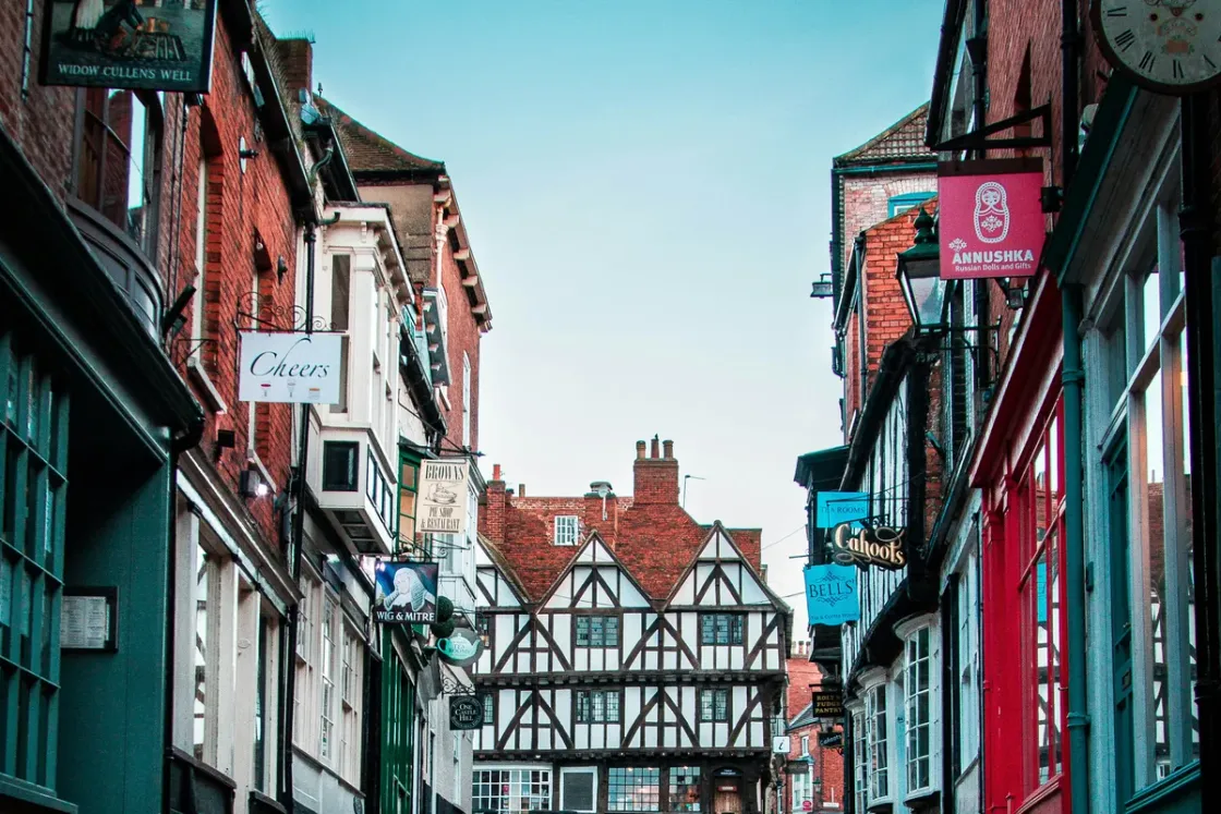 Independent shop and pub signs hanging along the cobbles of Steep Hill in Lincoln